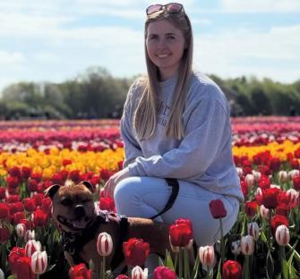 Woman kneeling in a tulip field with her dog.