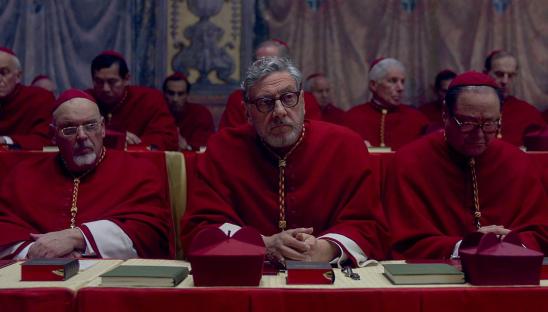 A group of cardinals in red robes seated at a table.