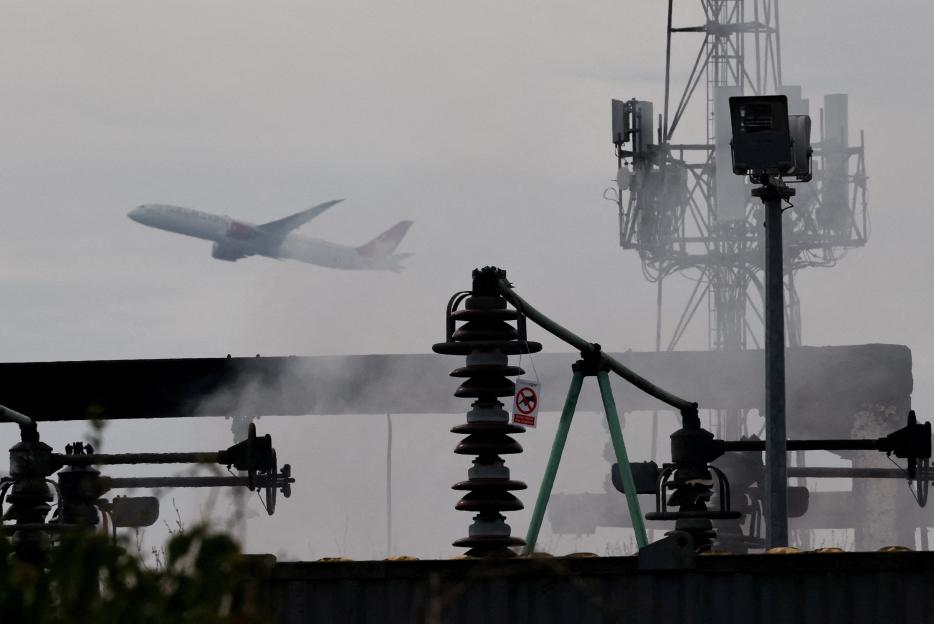 Plane taking off over a smoking electrical substation.