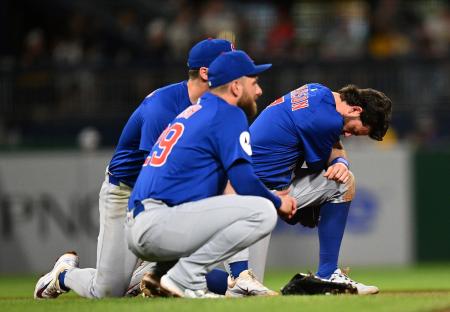 Three Chicago Cubs baseball players kneeling on the field.
