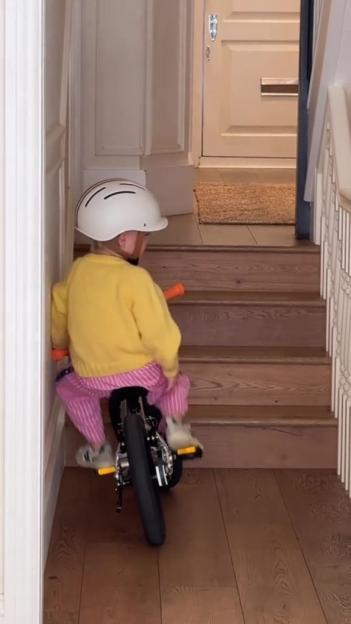 Toddler on balance bike near stairs.