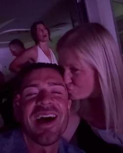 A man laughing while a woman kisses his cheek.
