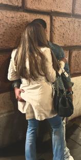 A woman and man embracing against a wall.