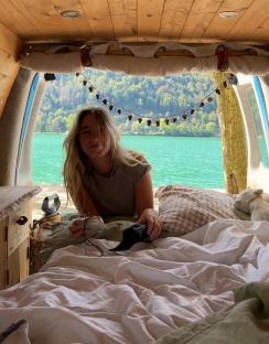 Woman relaxing in her van by a lake.
