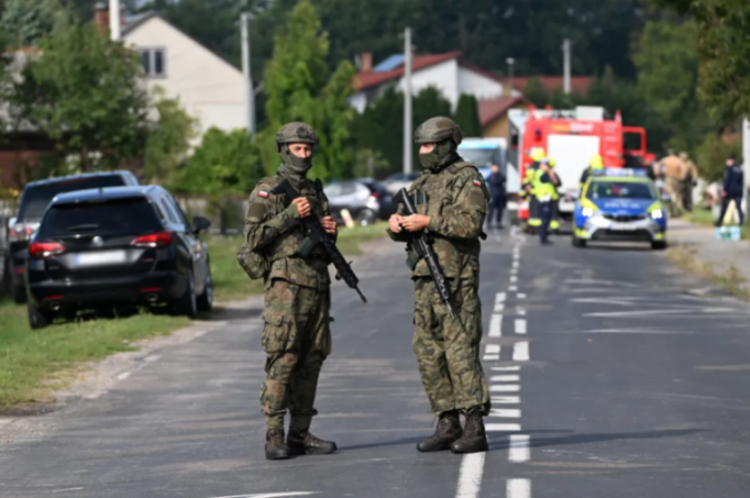 Two armed soldiers standing on a road.