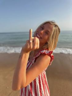 Woman showing off engagement ring on beach.