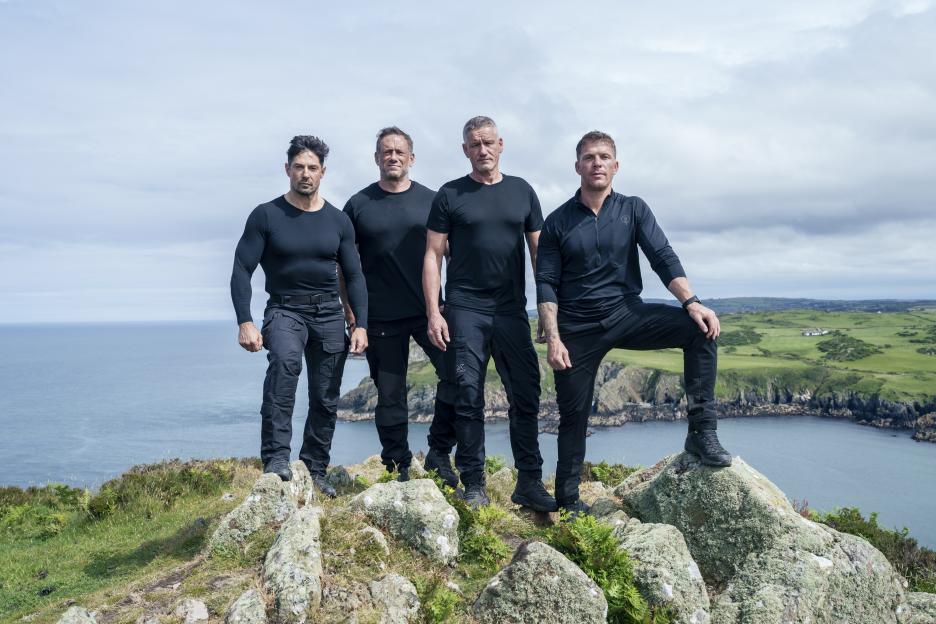 Four instructors from Celebrity SAS: Who Dares Wins standing on rocks overlooking the ocean.