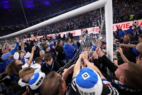 Fans celebrating a soccer team's promotion by ripping down the goal net.