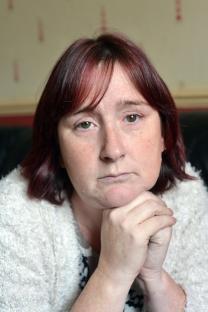 Portrait of a woman with red hair, looking somber.