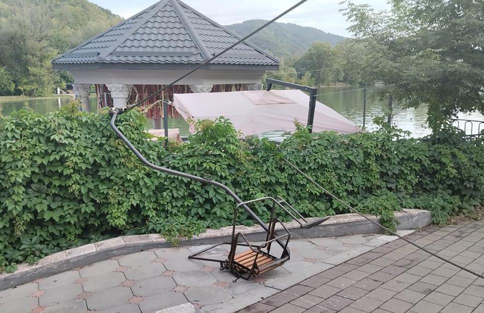 Damaged chairlift on the ground near a lake.