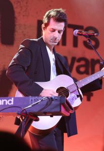 Mark Ronson performing onstage with a guitar and keyboard.