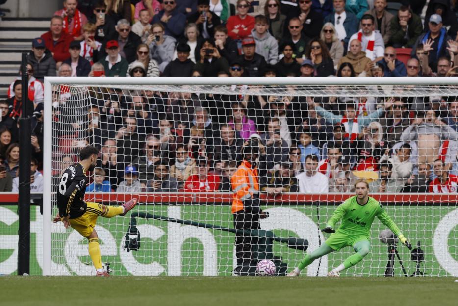 Bruno Fernandes takes a penalty kick while Brentford's Caoimhin Kelleher saves it.