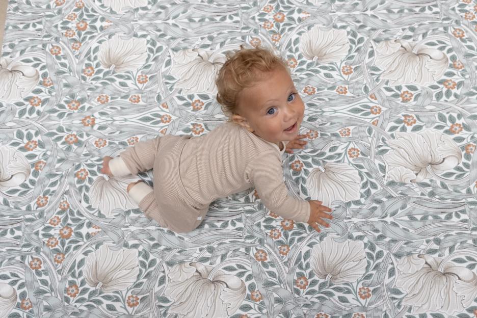 Baby in beige outfit on patterned baby bouncer.