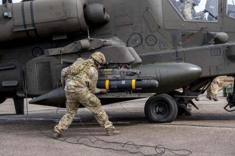 A soldier loading a Hellfire missile onto an Apache helicopter.