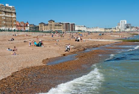 Crowded beach at Hove, East Sussex, with buildings in the background.