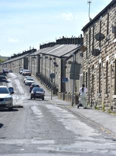 A woman pushes a stroller down a residential street in Burnley, Lancashire.