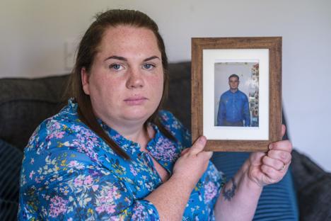 Woman holding a framed photo of her deceased brother.