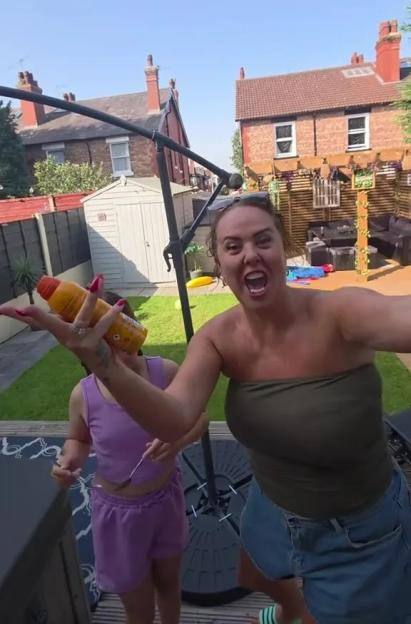 Woman applying sunscreen to child in backyard.