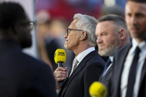 Man in suit and glasses speaking on television.
