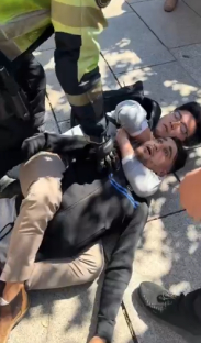 A person being restrained on the ground by another person.