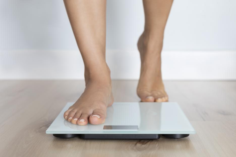 Barefoot female about to step on a weighing scale.