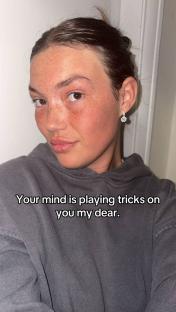 Close-up of a woman's face with freckles, wearing a gray hoodie. Text overlay reads: "Your mind is playing tricks on you my dear."