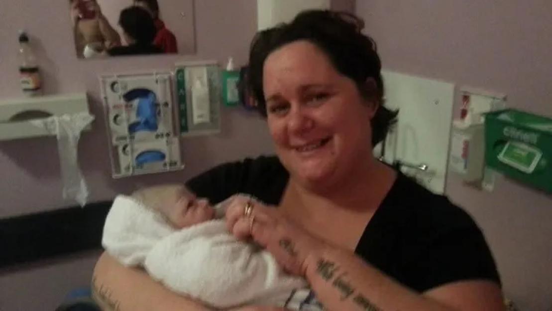 A mother holding her newborn baby in a hospital room.