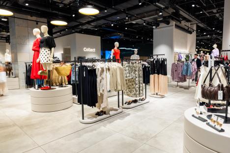 Clothing store interior with mannequins and clothing displays.