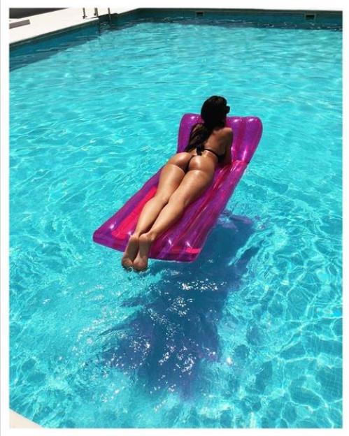 a woman in a bikini is laying on a pink raft in a pool