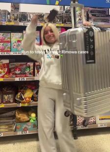 Person in Tesco holding a large silver suitcase.