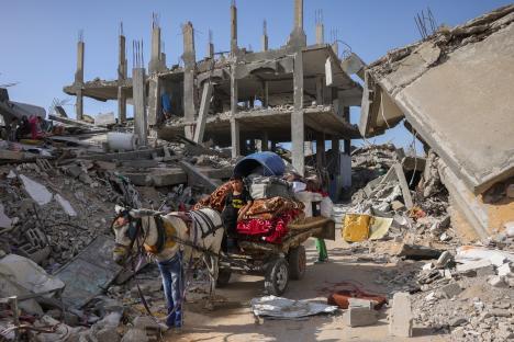 Palestinians fleeing the northern Gaza Strip with their belongings on a horse-drawn cart amidst destroyed buildings.