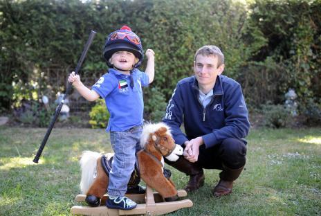Jockey Ryan Moore with his young son on a rocking horse.