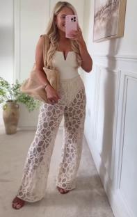 Woman modeling a white top and beige lace pants.