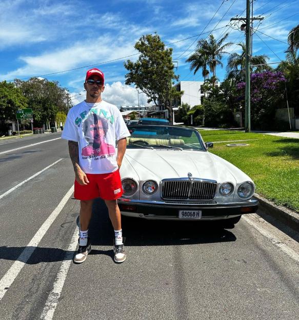 Lewis Hamilton standing in front of a white convertible car.