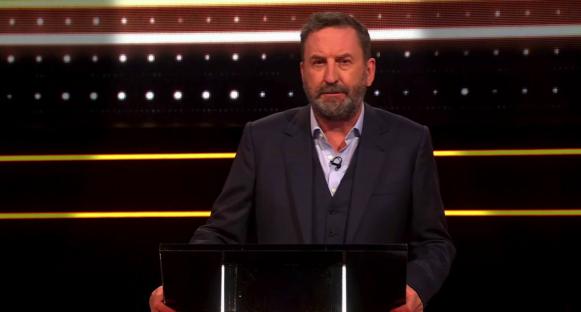 Screenshot of a man at a podium on a game show.