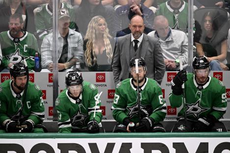 Dallas Stars head coach Peter DeBoer and players on the bench during a hockey game.