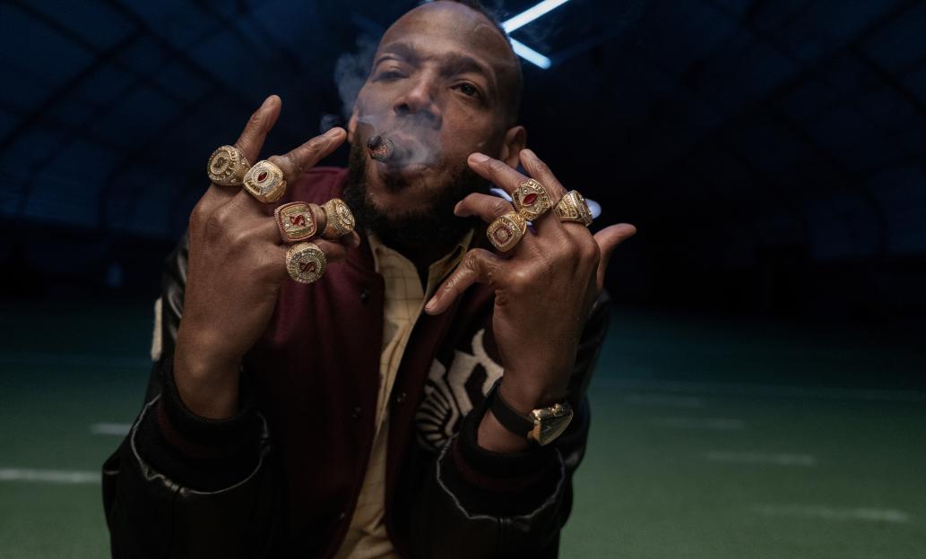 Marlon Wayans as Isaiah with championship rings on his fingers, smoking a cigar.