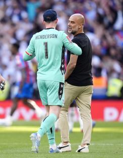 Dean Henderson and Pep Guardiola talking on a soccer field.