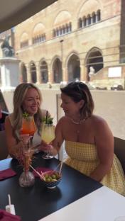 Two women enjoying cocktails at an outdoor cafe.