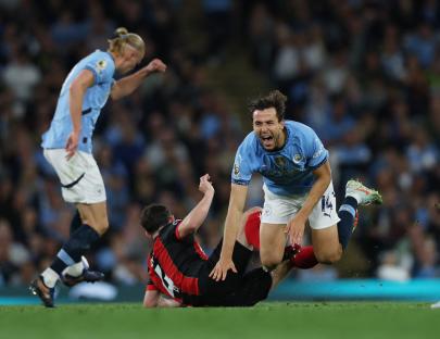 A soccer player from Manchester City fouls an AFC Bournemouth player, resulting in a red card.