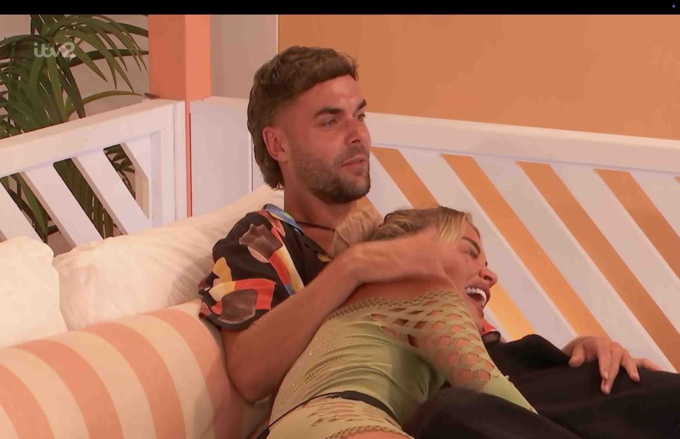 Love Island couple embracing on a couch.