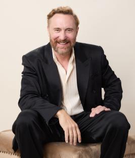 Portrait of David Guetta smiling while sitting.