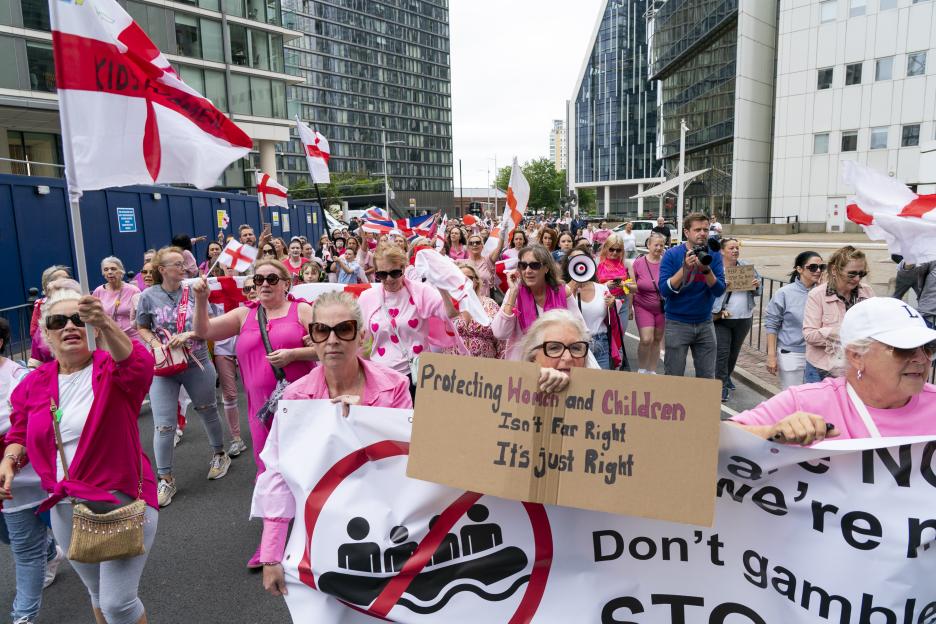 Protestors marching with signs against immigration.