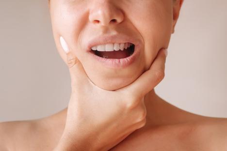 Close-up of a young woman holding her jaw, experiencing pain.