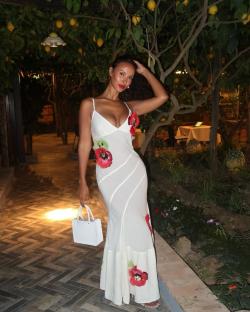 Maya Jama in a white maxi dress with red floral appliquÃ©s.