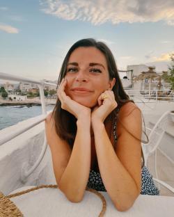 Woman with her chin resting on her hands, smiling at the camera.