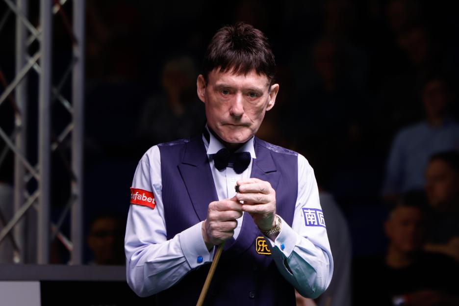 Snooker player Jimmy White chalking his cue.