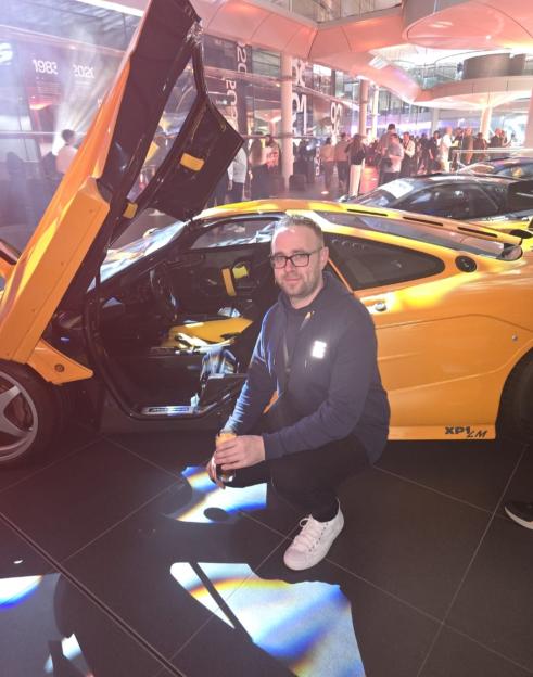 Man crouching next to a yellow McLaren F1.
