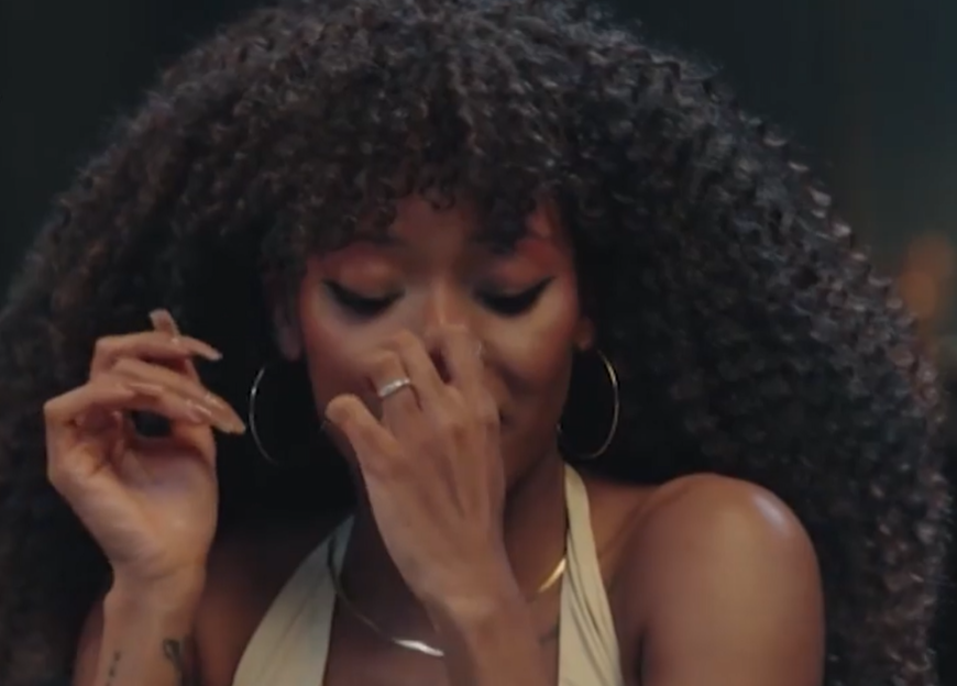 A woman with curly hair covers her nose with her hand.