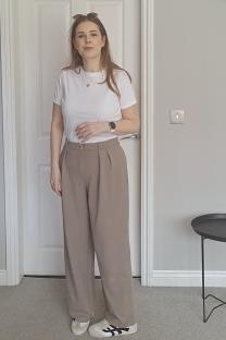 Woman wearing a white shirt and taupe pants.